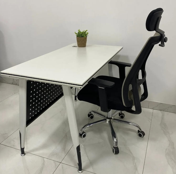 White office desk with a black chair on a tiled floor.
